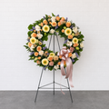Floral wreath with a pink bow on a stand against a white background